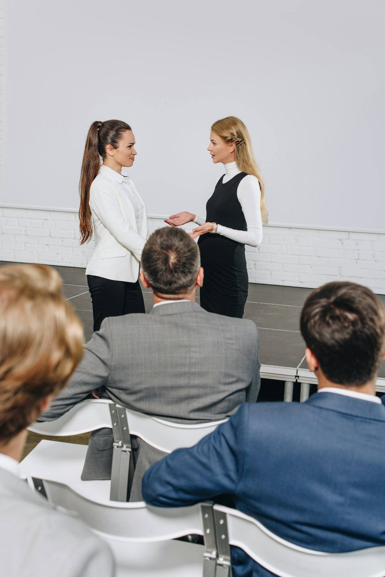 attractive business coach and businesswoman talking at training in hub